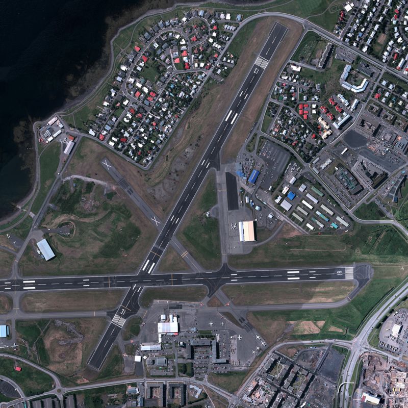 Aerial view of an airport with multiple runways, taxiways, and surrounding buildings