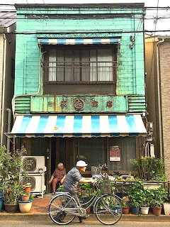 Turquoise vintage shop front with bicycle and plants on sidewalk