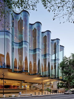 Modern theater building with a curved glass facade and glowing interior windows