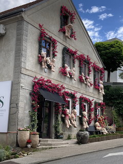 European building facade decorated with red climbing flowers and figurines along the walls and windows