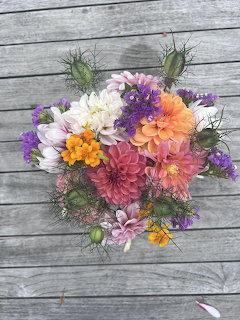 Vibrant autumn bouquet with dahlias and wildflowers in warm fall colors on rustic gray wood planks