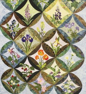Quilt with circular pattern showing various wildflowers in diamond and curved segments
