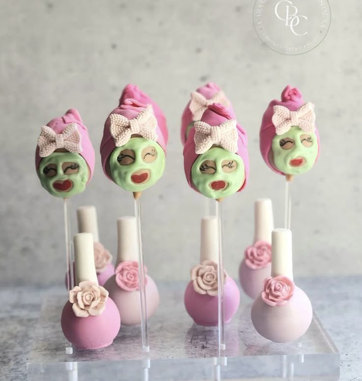 Four spa-themed cake pops with green face masks, pink towels, and rose decorations