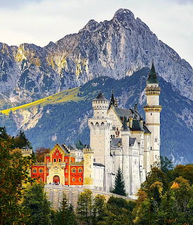 Neuschwanstein Castle on a wooded hill with steep mountains in the background