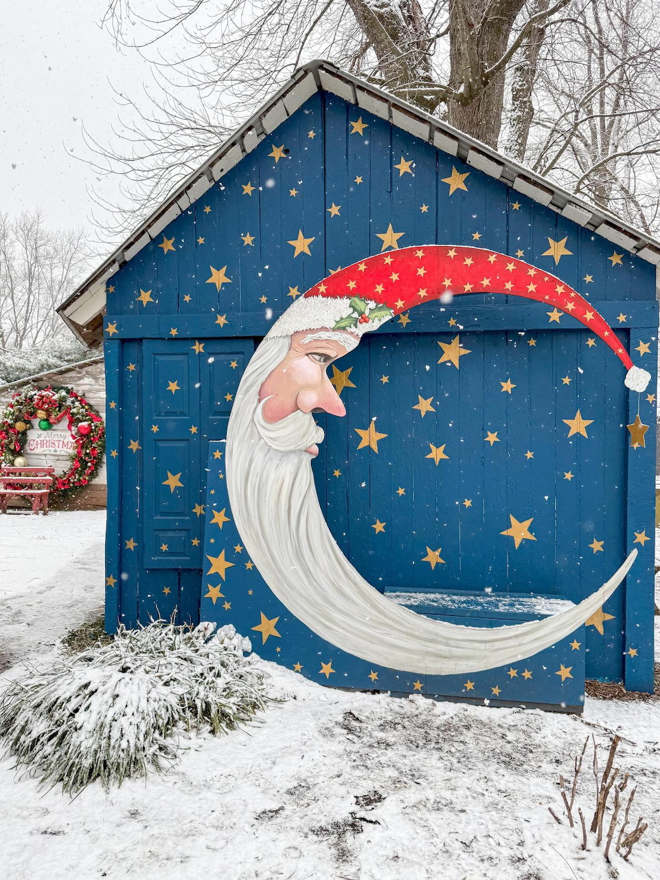 Blue shed with painted crescent moon face and stars in snowy yard