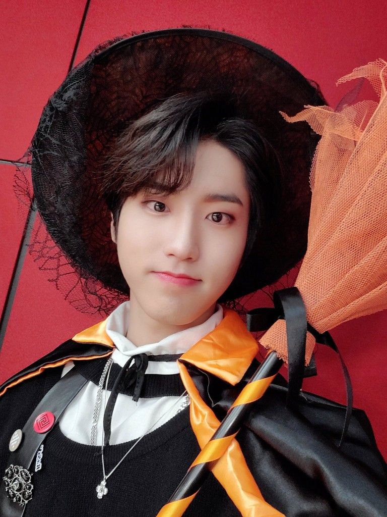 Person in costume with black hair, orange bow, and ornate outfit against red background