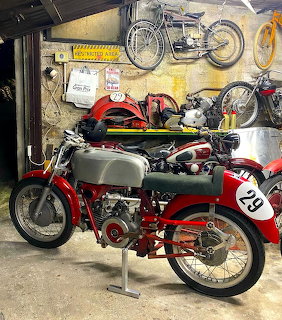 Red and silver vintage Moto Guzzi racing motorcycle number 28 on display stand in motorcycle workshop