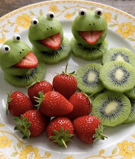 Cute frog faces made from kiwi slices and strawberries on a white floral plate