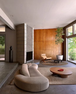 Minimalist living room with curved sofa, lounge chair, coffee table, and tall windows