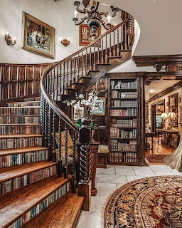 Curved wooden staircase beside tall bookshelves in an elegant library interior