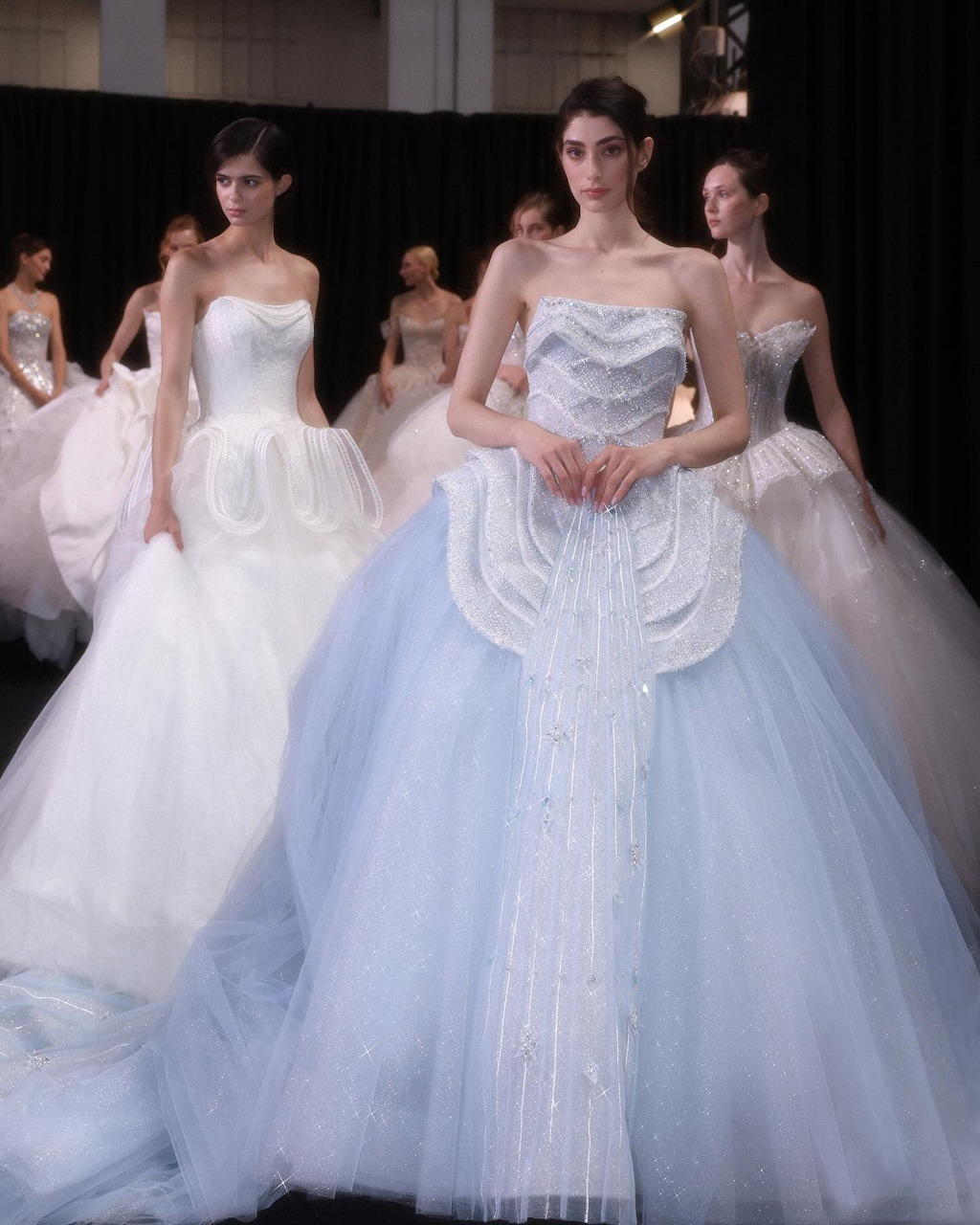 Fashion models in white wedding gowns walking on a runway