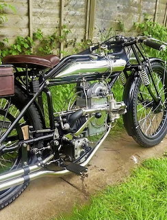 Vintage 1922 Brough motorcycle with chrome tank parked on grass