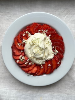 White plate with sliced strawberries arranged around vanilla ice cream scoop, overhead view