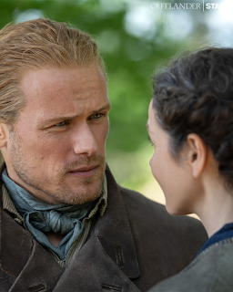 Close-up of a man and woman in period costume facing each other outdoors