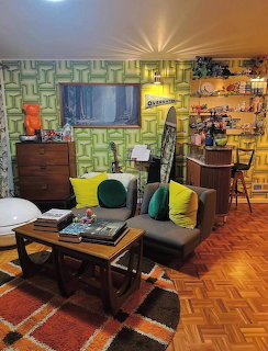 Retro living room with mid-century furniture, green geometric wallpaper, and colorful throw pillows