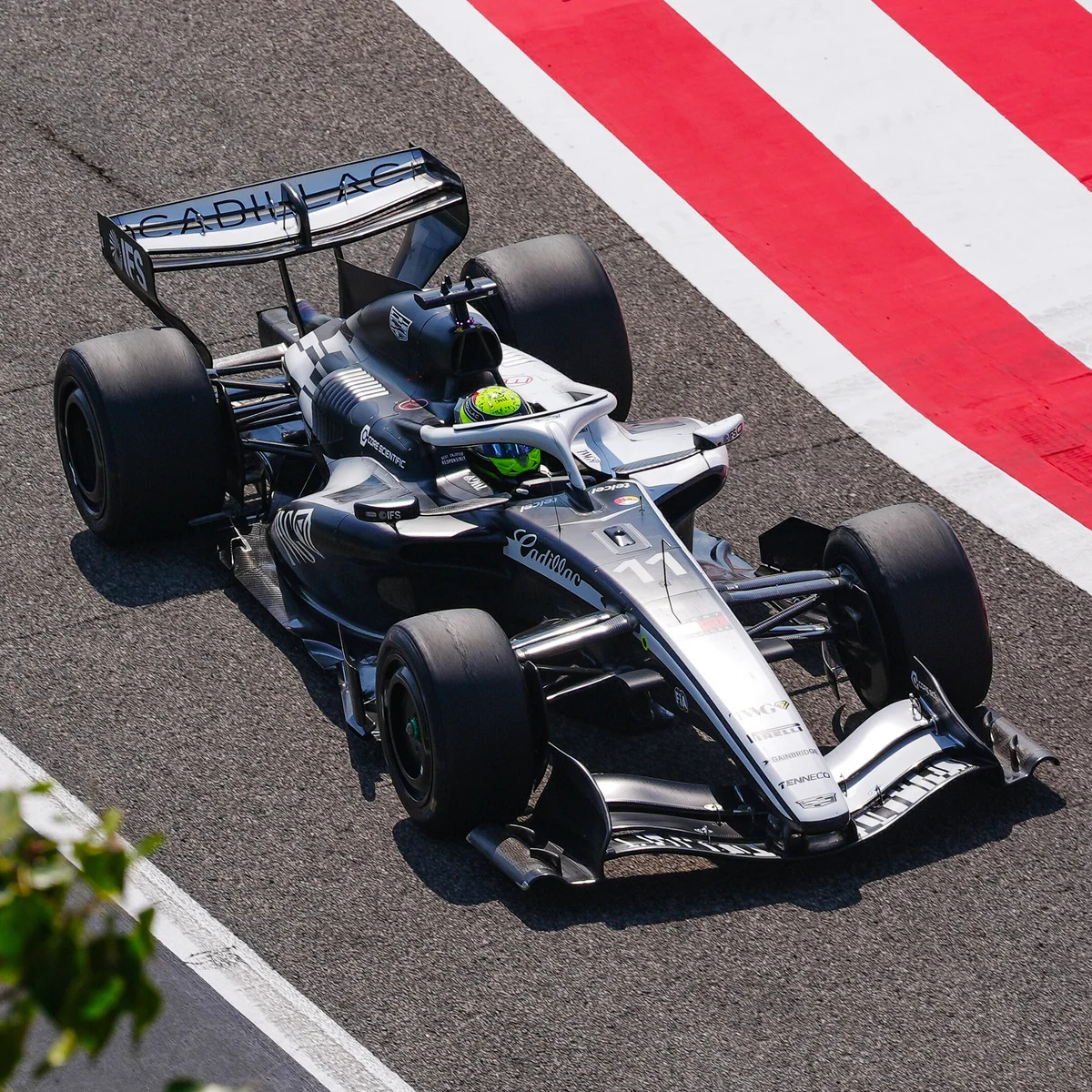 Black open-wheel formula race car on a racetrack next to a red and white curb