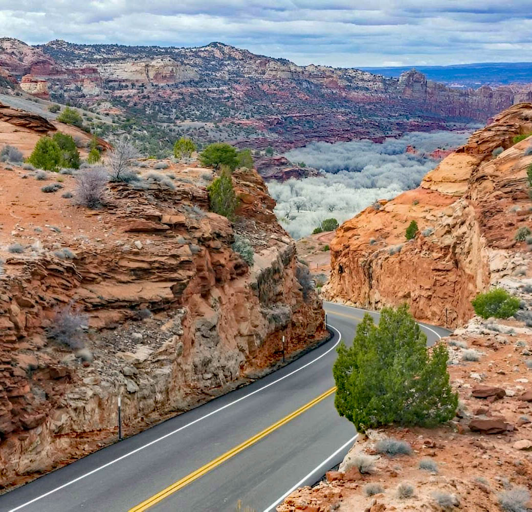 Curved highway through red sandstone canyon with mountains in background