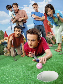 Group portrait of Malcolm in the Middle TV show cast posing playfully on artificial turf with a golf ball