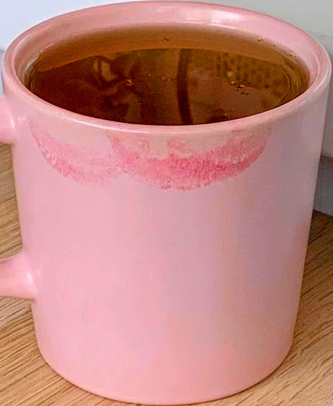 Black coffee in a light pink ceramic mug on a wooden table