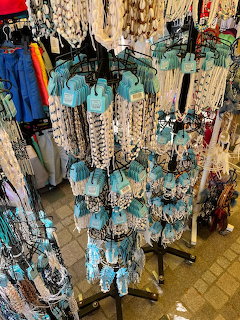 Display of turquoise and white seashell necklaces hanging on retail stands in a beach souvenir shop