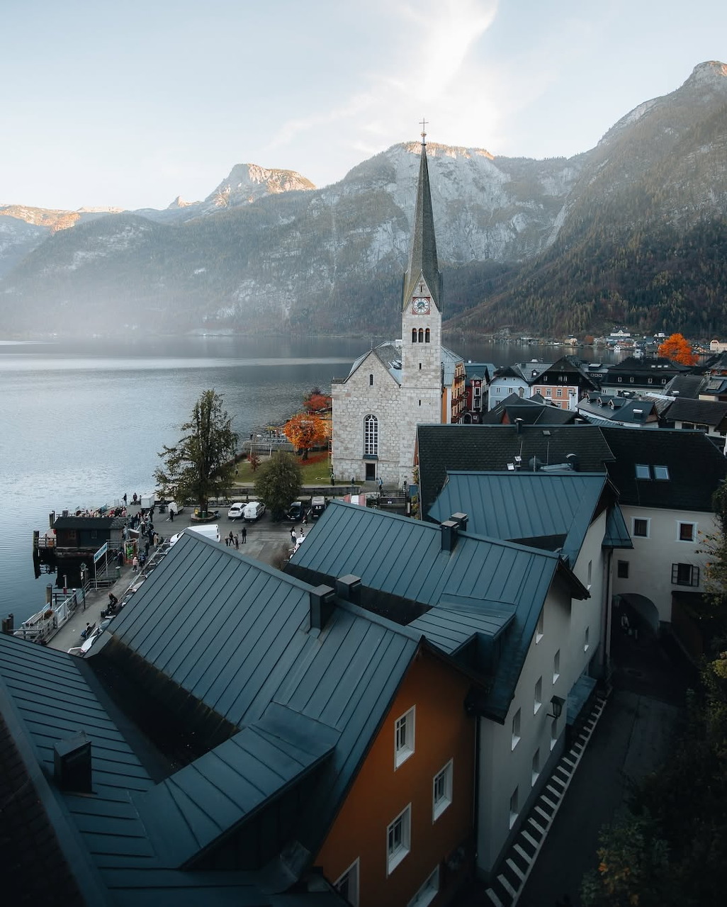 Aerial view of Hallstatt Austria with church spire, alpine lake, and snow-capped mountains