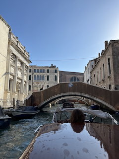 Stone bridge arching over a Venice canal viewed from a boat, with historic buildings on both sides