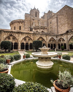 Tarragona Cathedral cloister with stone arches, fountain, and garden courtyard