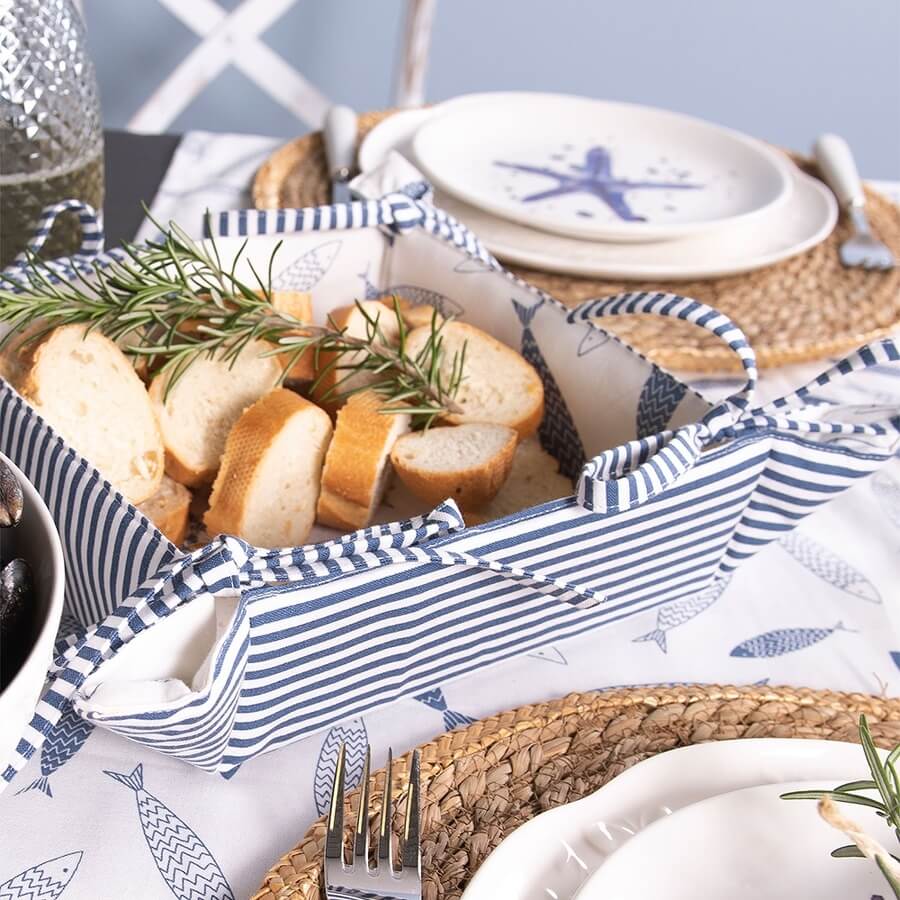Sliced bread in a blue and white striped cloth basket on a nautical-themed table setting