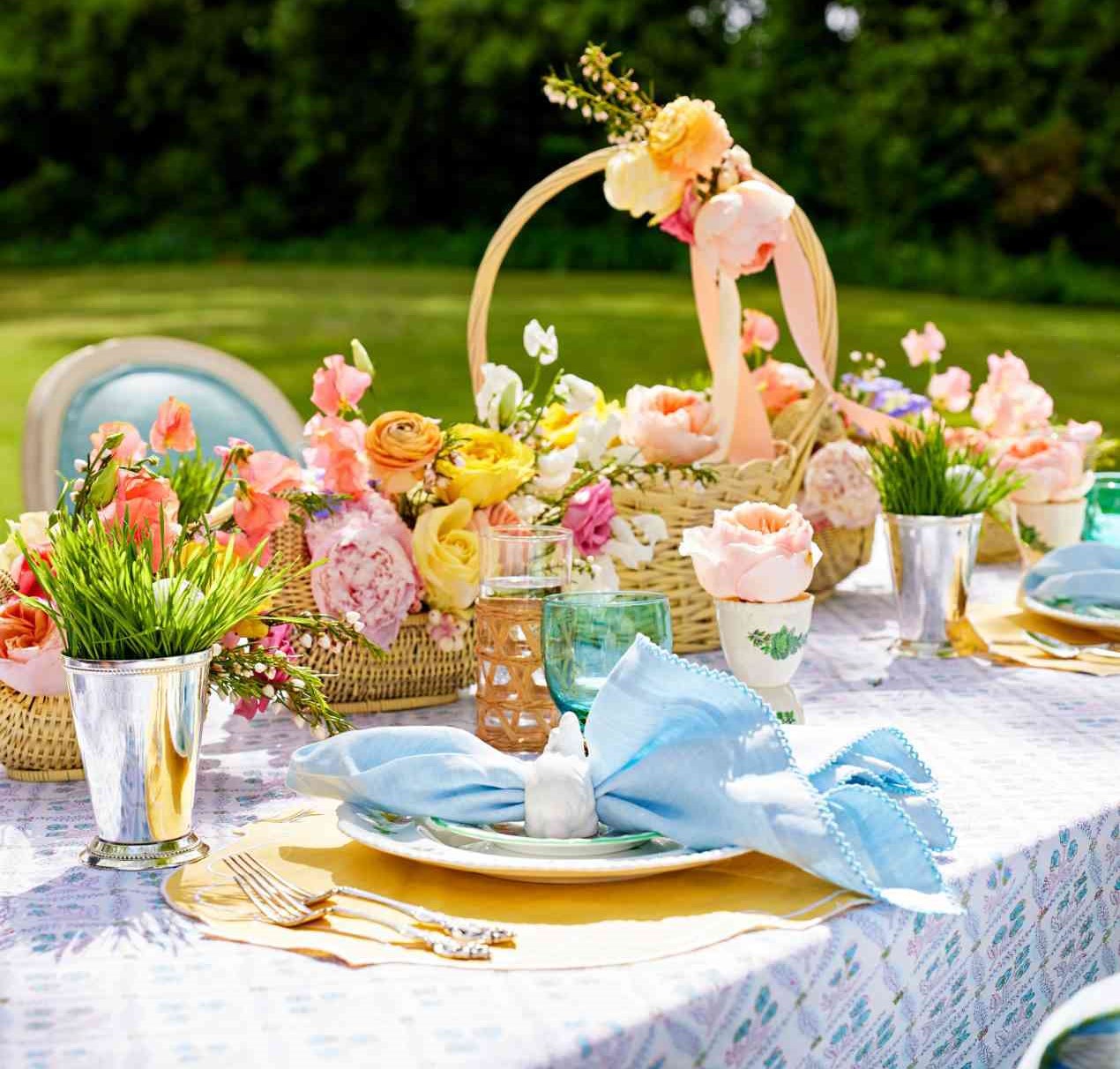 Colorful Easter table setting outdoors with eggs, flowers, pastel tableware, and spring decorations