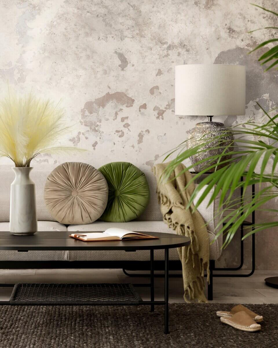 Bench with green and taupe round pillows, palm plant, table lamp, and textured wall in a modern interior