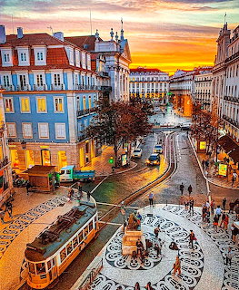 Sunset view of Lisbon square with vintage tram, historic buildings, fountain, and colorful sky