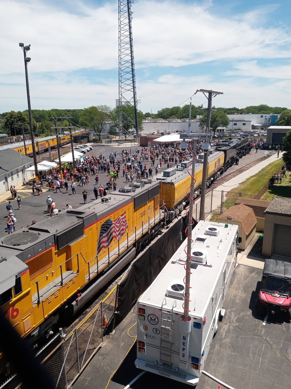 Aerial view of a yellow Union Pacific train at a station with crowds of people gathered along the tracks