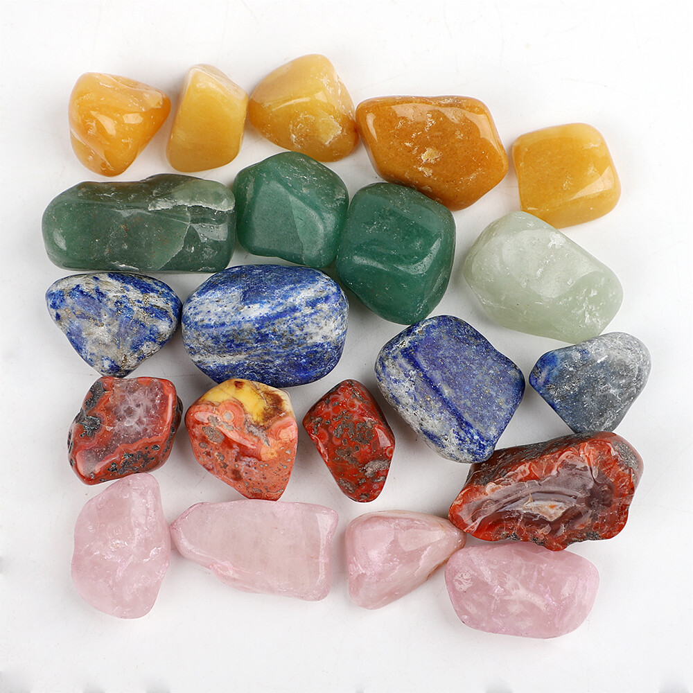 Assorted polished gemstones in multiple colors arranged on a white background
