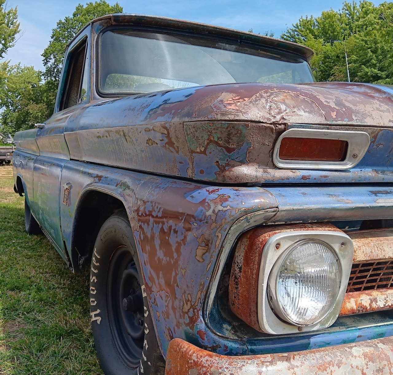 Close-up of a rusty blue vintage Chevrolet C10 pickup truck parked outdoors