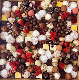 Dense collection of assorted chocolate truffles, pralines, and colorful confections arranged together