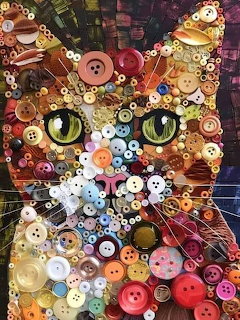 Cat face mosaic made of colorful buttons, beads, and circular objects with striking green eyes