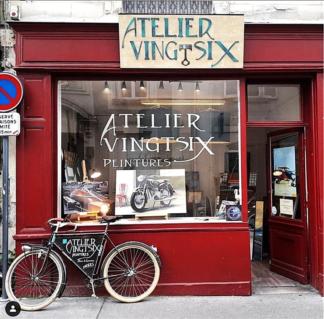 Red French art shop facade with bicycle parked outside and large windows displaying artwork