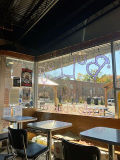 Cafe interior with white tables, chairs, large windows and exposed industrial ceiling