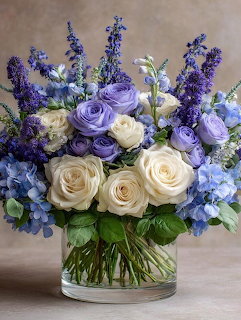 Bouquet of cream roses, purple flowers including lavender and lisianthus in glass vase