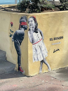 Street mural of boy giving rose to girl on yellow wall