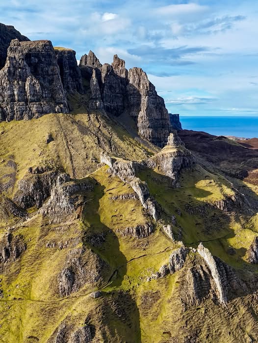 Rugged rocky mountain cliffs and green hills at the Quiraing, Scotland, with ocean view