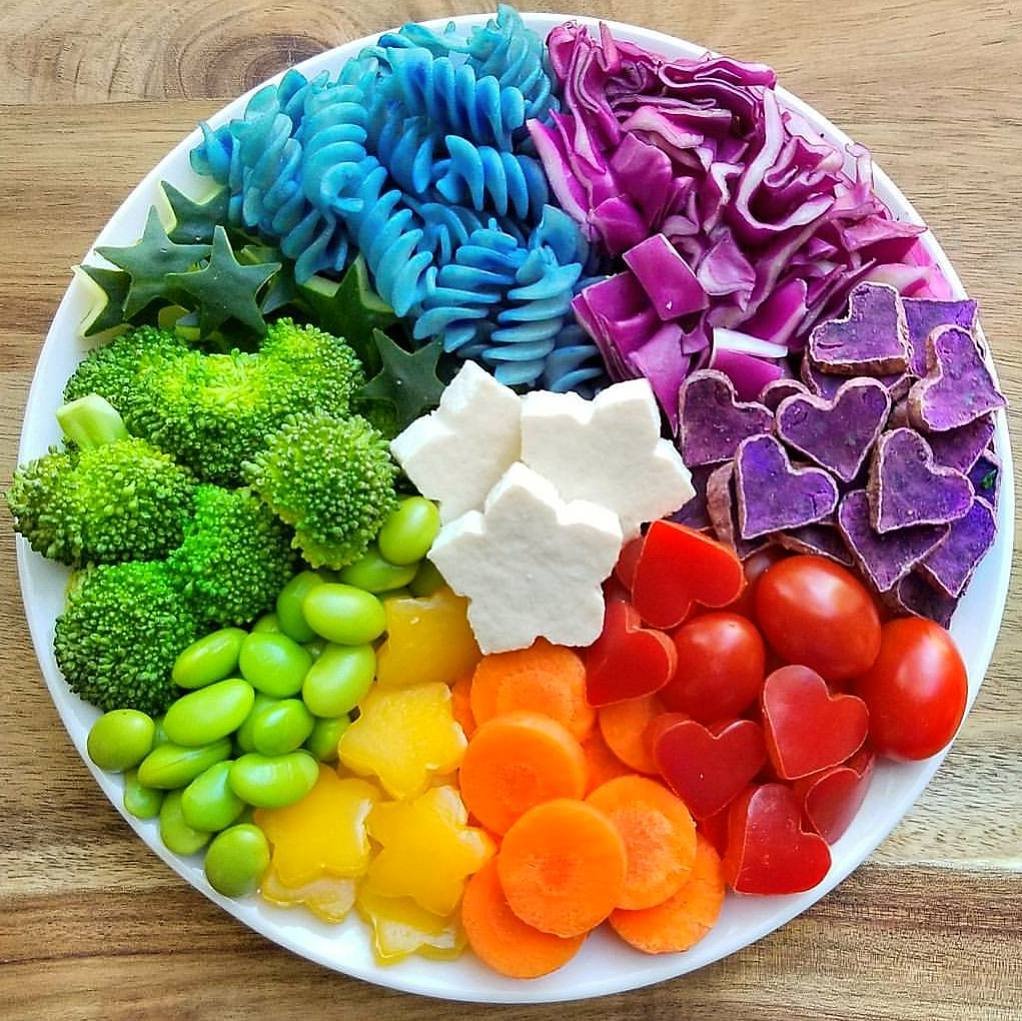 Circular platter of vegetables arranged in rainbow colors from green to red with white cauliflower center