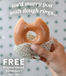Hand holding heart-shaped glazed donut with white sprinkles against polka dot background