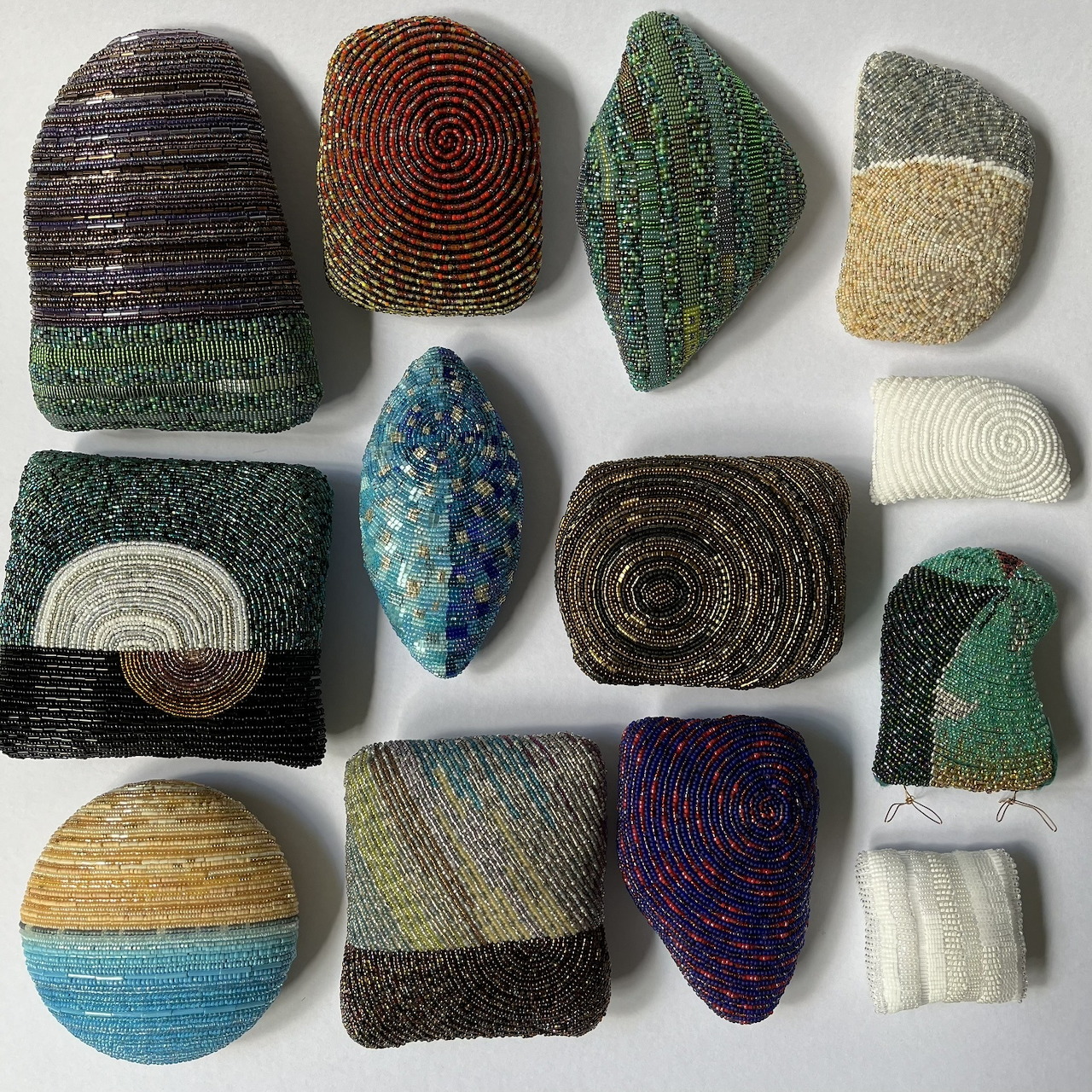 Abstract beaded and woven shapes displayed on a white background