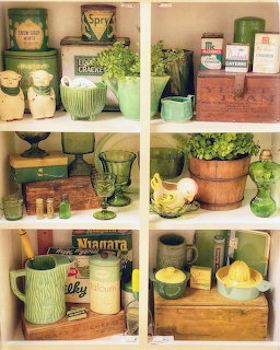 Vintage green kitchen items arranged on wooden shelves with pottery, canisters, and plants