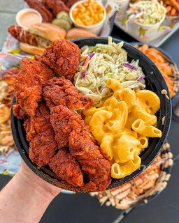 Cast iron skillet with fried chicken tenders, macaroni and cheese, coleslaw, and corn served at an outdoor table
