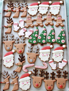 Assorted decorated Christmas cookies including Santa faces, reindeer, trees, and gingerbread men on a baking sheet