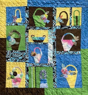 Patchwork quilt with appliqued baskets and flowers in blue, yellow, green, and brown squares