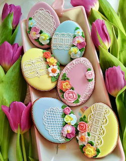 Easter egg cookies with colorful icing and flowers on white plate with purple tulips