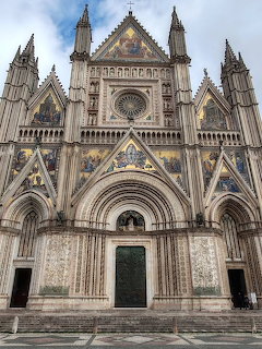 Gothic facade of Orvieto Cathedral with golden mosaics, spires, and ornate marble details